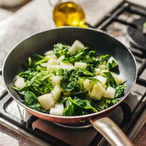 Fresh spinach leaves and crisp fennel pieces sautéed to perfection in a pan drizzled with olive oil, creating a harmonious medley of greens for a gastritis-friendly omelette base.